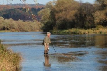 Fly fisherman Lawrence Greasley contemplates the island water at Zaluz on the San River in Poland.
